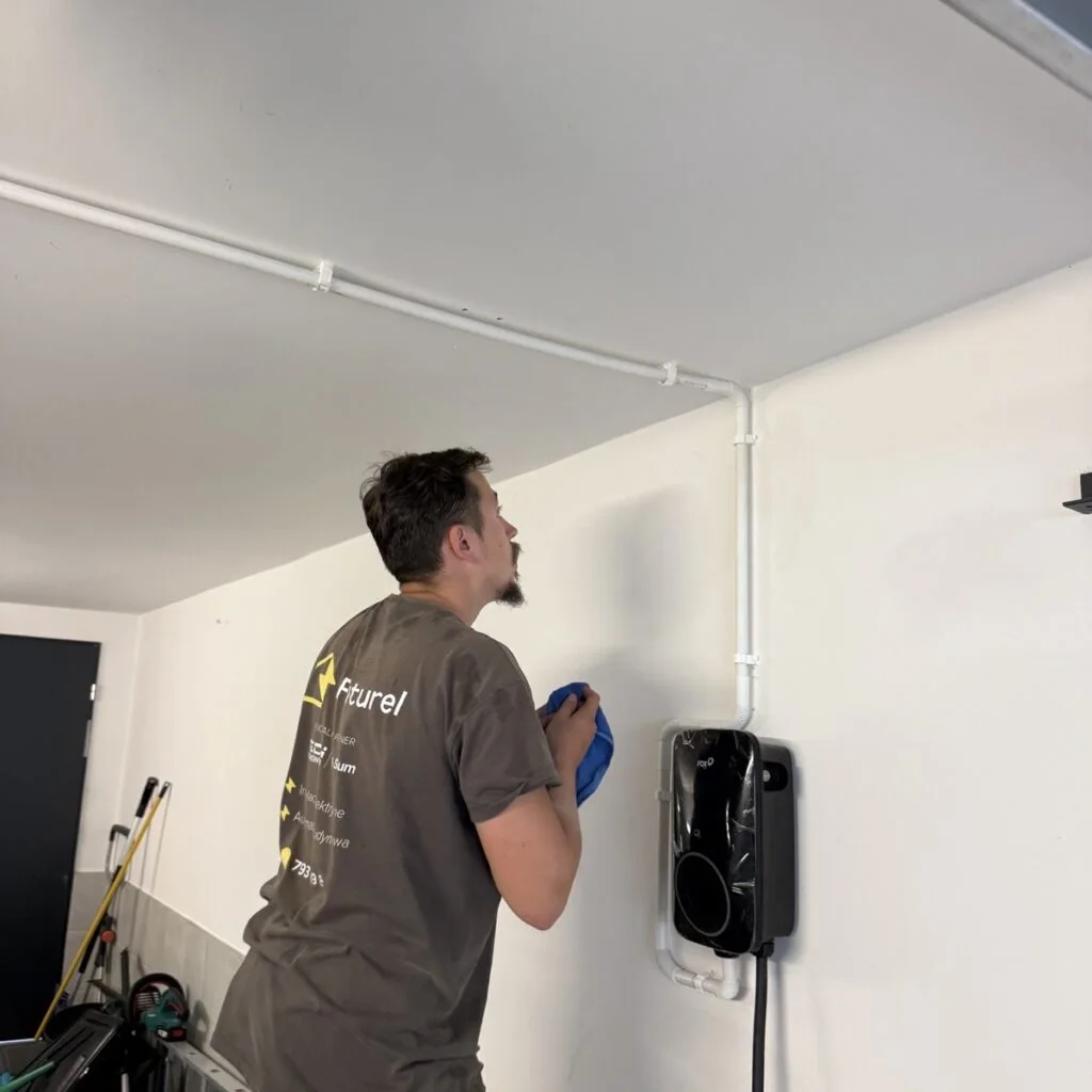 Technik Futurel w firmowej koszulce montujący instalację w garażu