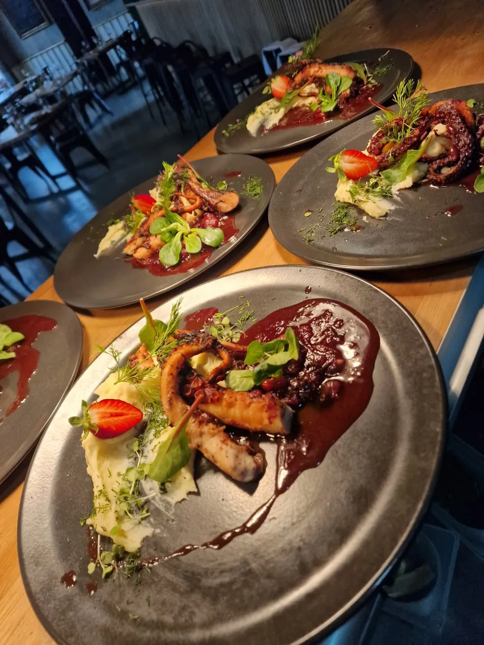 Grillowana ośmiornica z puree i sałatą na ciemnych talerzach