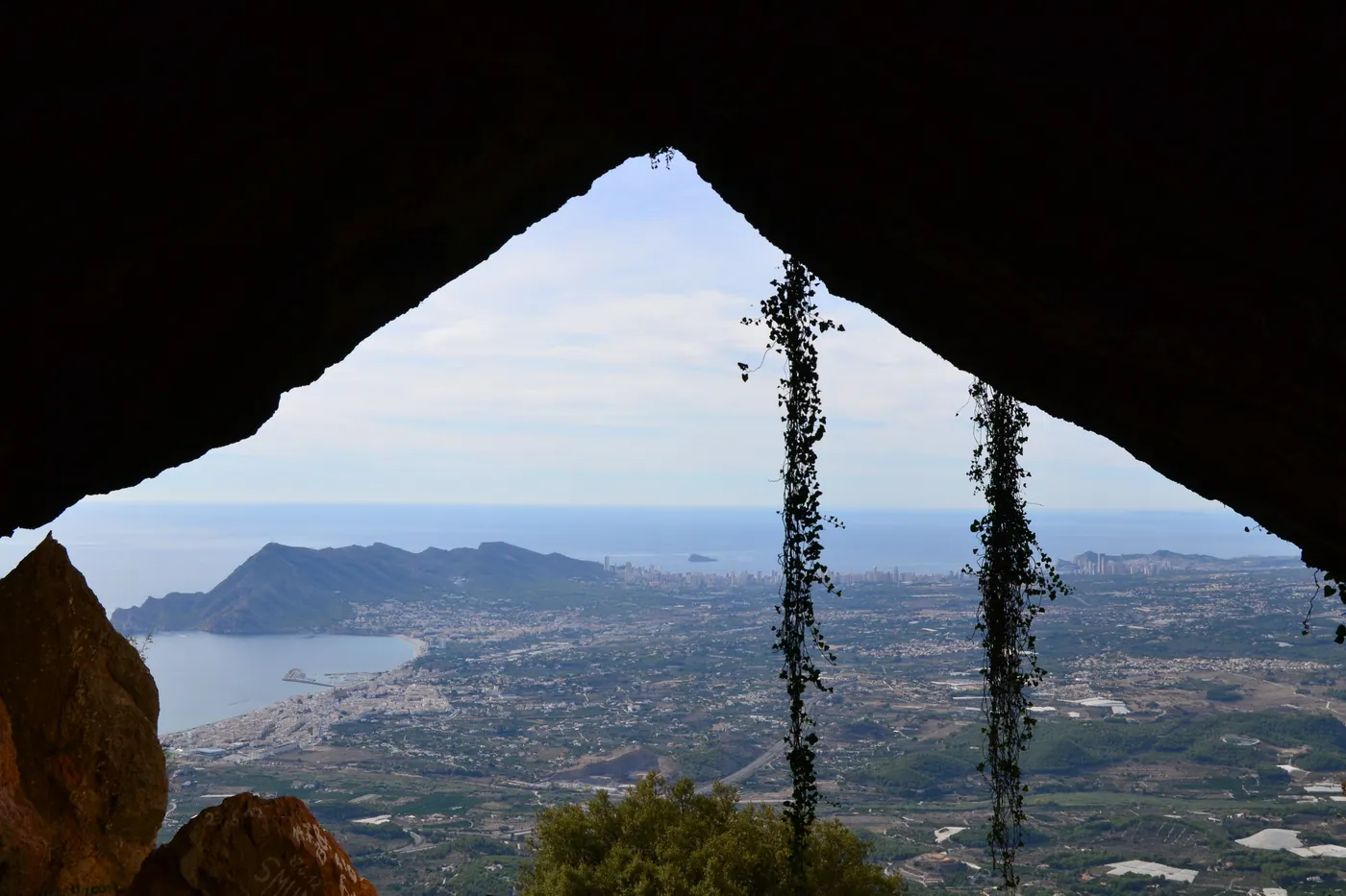 Widok przez naturalny tunel El Forat w Sierra de Bernia na wybrzeże Calpe i Altei